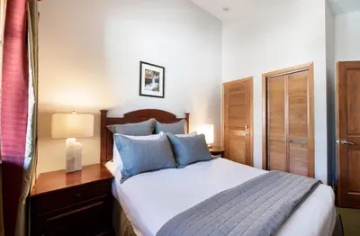 a bedroom with a bed with blue pillows and a desk at Comfortable Mountain Adventure Condo at Zephyr Mountain Lodge with Village View condo in Winter Park