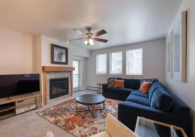 a living room with a blue couch and a fireplace at Comfortable Fraser Crossing Founders Pointe Condo with Easy Access to the Gondola condo in Winter Park