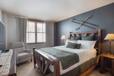 a bedroom with a large bed and a chair at Cozy Lower Hughes View 2 BR Zephyr Mountain Lodge Condo with Ski Storage condo in Winter Park