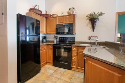 a kitchen with a black refrigerator and wooden cabinets at Terrific Zephyr Mountain Lodge Condo With Beautiful Views of the Slopes condo in Winter Park