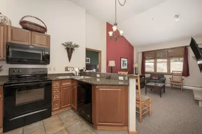 a kitchen with a stove top oven next to a living room at Terrific Zephyr Mountain Lodge Condo With Beautiful Views of the Slopes condo in Winter Park