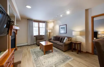 a living room with a couch and a tv at Recently remodeled third floor Zephyr Mountain Lodge condo with trail view condo in Winter Park