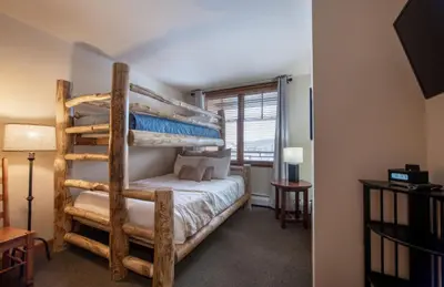 a bedroom with two bunk beds and a lamp at Recently remodeled third floor Zephyr Mountain Lodge condo with trail view condo in Winter Park