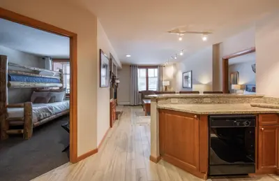a kitchen and living room with a bed in the background at Recently remodeled third floor Zephyr Mountain Lodge condo with trail view condo in Winter Park