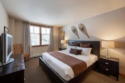 a bedroom with a large bed and a television at Recently remodeled third floor Zephyr Mountain Lodge condo with trail view condo in Winter Park