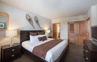 a bedroom with a large bed and a flat screen tv at Recently remodeled third floor Zephyr Mountain Lodge condo with trail view condo in Winter Park
