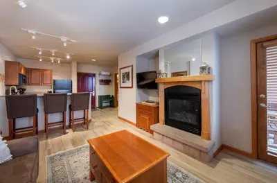 a living room with a fireplace and a kitchen at Recently remodeled third floor Zephyr Mountain Lodge condo with trail view condo in Winter Park