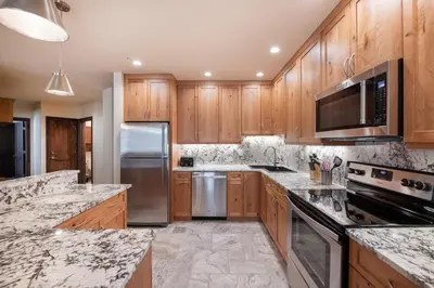 a kitchen with wooden cabinets and stainless steel appliances at Spectacular Ski-In Ski-Out Zephyr Mountain Lodge Condo with Village Corridor View condo in Winter Park