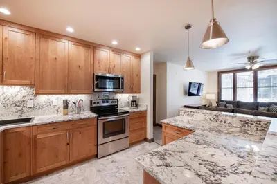 a kitchen with wooden cabinets and a stove top oven at Spectacular Ski-In Ski-Out Zephyr Mountain Lodge Condo with Village Corridor View condo in Winter Park