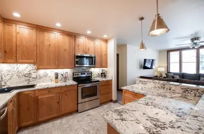 a kitchen with wooden cabinets and a stove top oven at Spectacular Ski-In Ski-Out Zephyr Mountain Lodge Condo with Village Corridor View condo in Winter Park