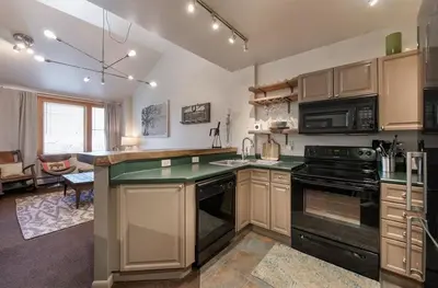 a large kitchen with a stove top oven next to a living room at Lovely Mountain Adventure Zephyr Mountain Lodge Condo with Ski Storage condo in Winter Park