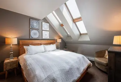 a bedroom with a large bed with skylights and a chair at Lovely Mountain Adventure Zephyr Mountain Lodge Condo with Ski Storage condo in Winter Park