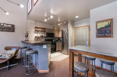 a kitchen with a bar and stools in a room at Lovely Mountain Adventure Zephyr Mountain Lodge Condo with Ski Storage condo in Winter Park
