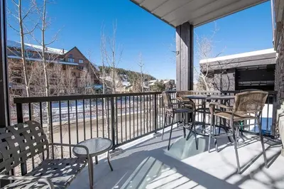 a balcony with a table and chairs and a view of the snow at Beautiful Ski-In Ski-Out Condo at Fraser Crossing Founders Pointe condo in Winter Park