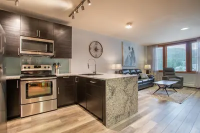 a kitchen with a stove top oven next to a living room at Beautiful Zephyr Mountain Lodge Condo with wine coole! - Close to Gondola! condo in Winter Park