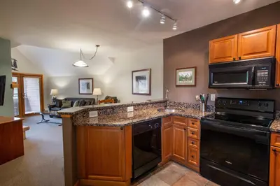 a kitchen with wooden cabinets and black appliances at Unique & Comfortable Zephyr Mountain Lodge Condo with Slope and Continental Divide View condo in Winter Park