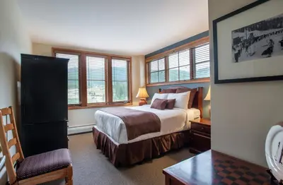 a bedroom with a bed and a chair and windows at Unique & Comfortable Zephyr Mountain Lodge Condo with Slope and Continental Divide View condo in Winter Park