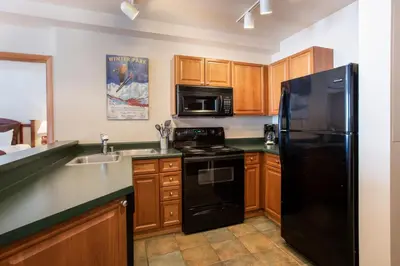 a kitchen with a black refrigerator and a sink at Zephyr Mountain Lodge Condo with views of Arapahoe National Forest condo in Winter Park