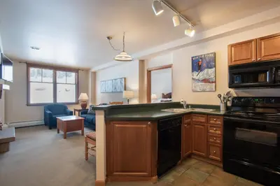 a kitchen with a black counter top and a living room at Zephyr Mountain Lodge Condo with views of Arapahoe National Forest condo in Winter Park