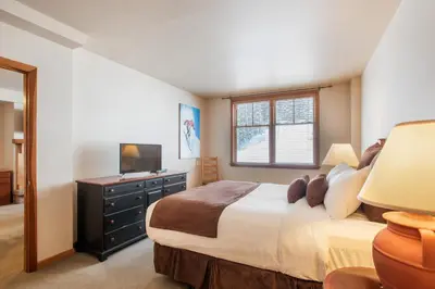 a bedroom with a bed with a dresser and a television at Zephyr Mountain Lodge Condo with views of Arapahoe National Forest condo in Winter Park