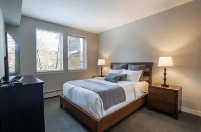 a bedroom with a bed and two windows at Beautiful Fraser Crossing Founders Pointe Condo with Upgraded Furnishings condo in Winter Park