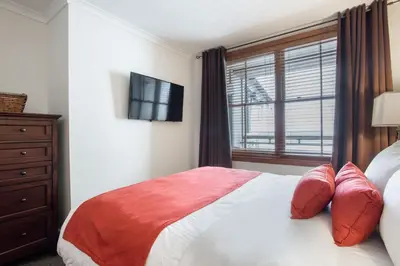 a bedroom with a bed with a window and a television at Gorgeous Zephyr Mountain Lodge Condo with Corridor Ski Trail Views condo in Winter Park