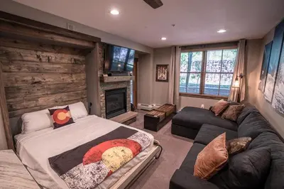 a bedroom with a bed and a couch and a fireplace at Striking and Unique Zephyr Mountain Lodge Condo - second floor walkout condo in Winter Park