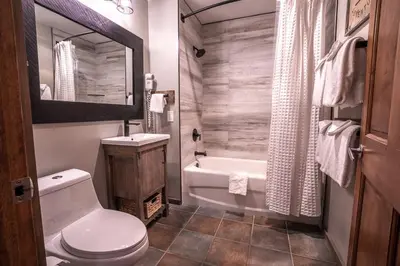 a bathroom with a toilet and a sink and a tub at Striking and Unique Zephyr Mountain Lodge Condo - second floor walkout condo in Winter Park