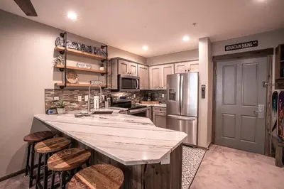 a kitchen with a counter and a refrigerator at Striking and Unique Zephyr Mountain Lodge Condo - second floor walkout condo in Winter Park