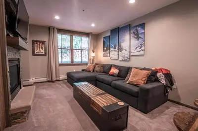 a living room with a couch and a tv at Striking and Unique Zephyr Mountain Lodge Condo - second floor walkout condo in Winter Park