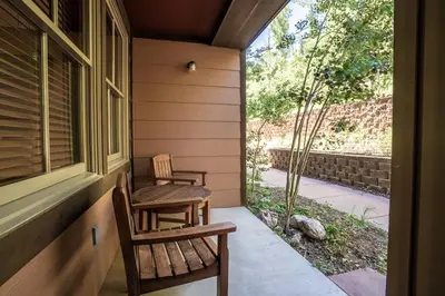a porch with two chairs and a table and a window at Striking and Unique Zephyr Mountain Lodge Condo - second floor walkout condo in Winter Park