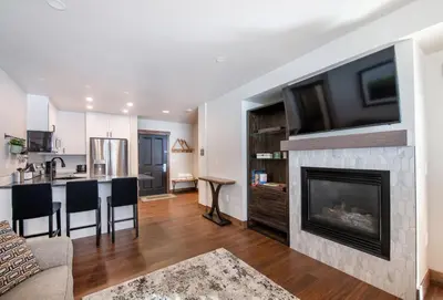 a living room with a fireplace with a tv above it at Warm & Cozy Zephyr Mountain Lodge condo with Arapahoe Forest and Corridor Ski Trail Views condo in Winter Park