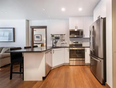 a kitchen with white cabinets and a stainless steel refrigerator at Warm & Cozy Zephyr Mountain Lodge condo with Arapahoe Forest and Corridor Ski Trail Views condo in Winter Park