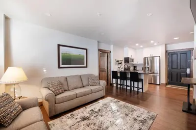 a living room with a couch and a kitchen at Warm & Cozy Zephyr Mountain Lodge condo with Arapahoe Forest and Corridor Ski Trail Views condo in Winter Park