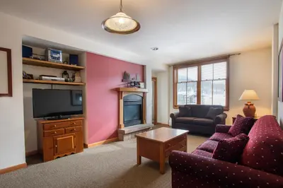 a living room with a couch and a tv at Great Ski-In Ski-Out Zephyr Mountain Lodge Condo with Lovely Balcony Views condo in Winter Park
