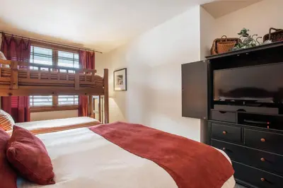 a bedroom with a bed and a flat screen tv at Great Ski-In Ski-Out Zephyr Mountain Lodge Condo with Lovely Balcony Views condo in Winter Park