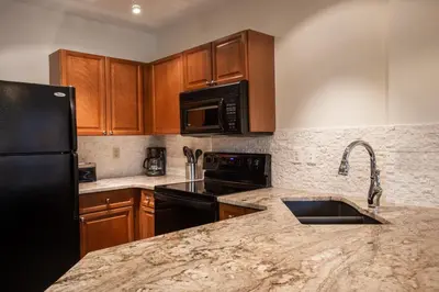 a kitchen with wooden cabinets and a black refrigerator at Remodeled Zephyr Mountain Lodge condo with upgraded furnishings and Slope Side View condo in Winter Park