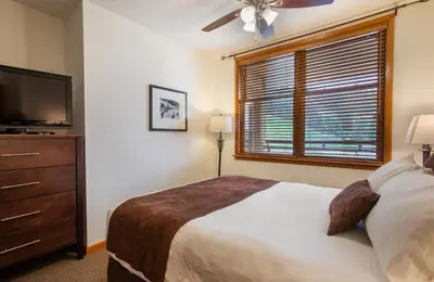 a bedroom with a bed and a television and a window at Remodeled Zephyr Mountain Lodge condo with upgraded furnishings and Slope Side View condo in Winter Park