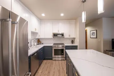 a kitchen with white cabinets and stainless steel appliances at Zephyr Mountain Lodge Premium-Rated 2505 in Winter Park