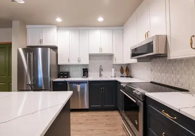 a kitchen with white cabinets and stainless steel appliances at Zephyr Mountain Lodge Premium-Rated 2505 in Winter Park