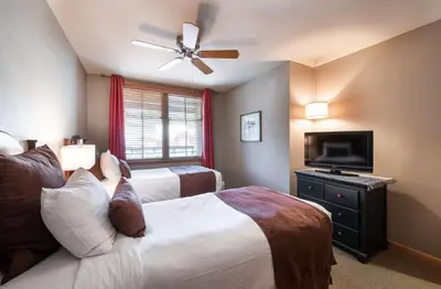 a bedroom with two beds and a flat screen tv at Zephyr Mountain Lodge Premium-Rated 1506 in Winter Park