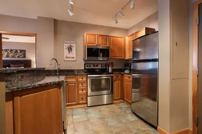 a kitchen with wooden cabinets and stainless steel appliances at Zephyr Mountain Lodge Premium-Rated 1506 in Winter Park