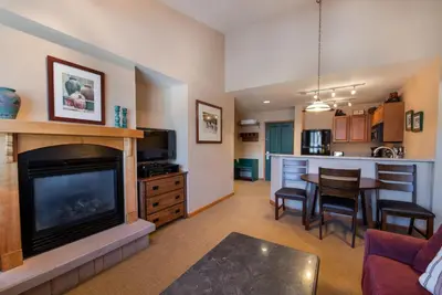 a living room with a fireplace and a kitchen at Zephyr Mountain Lodge Select-Rated 1604 in Winter Park