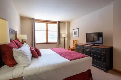 a bedroom with a large bed and a flat screen tv at Spectacular Zephyr Mountain Lodge Condo with Ski Slope View condo in Winter Park