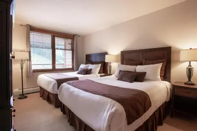 two beds in a bedroom with two lamps and a window at Spectacular Zephyr Mountain Lodge Condo with Ski Slope View condo in Winter Park