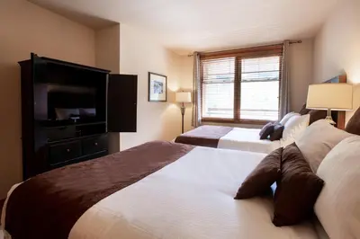 a bedroom with two beds and a flat screen tv at Spectacular Zephyr Mountain Lodge Condo with Ski Slope View condo in Winter Park