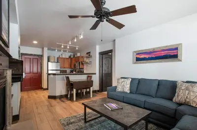 a living room with a blue couch and a ceiling fan at Cozy Zephyr Mountain Lodge condo with sweeping views of Arapahoe National Forest condo in Winter Park