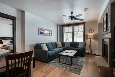 a living room with a blue couch and a table at Cozy Zephyr Mountain Lodge condo with sweeping views of Arapahoe National Forest condo in Winter Park