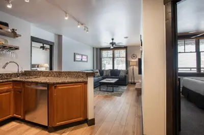 a kitchen with a sink and a living room at Cozy Zephyr Mountain Lodge condo with sweeping views of Arapahoe National Forest condo in Winter Park