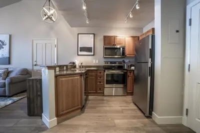 a kitchen with wooden cabinets and stainless steel appliances at Cozy Zephyr Mountain Lodge Condo with Spectacular View of Gondola condo in Winter Park
